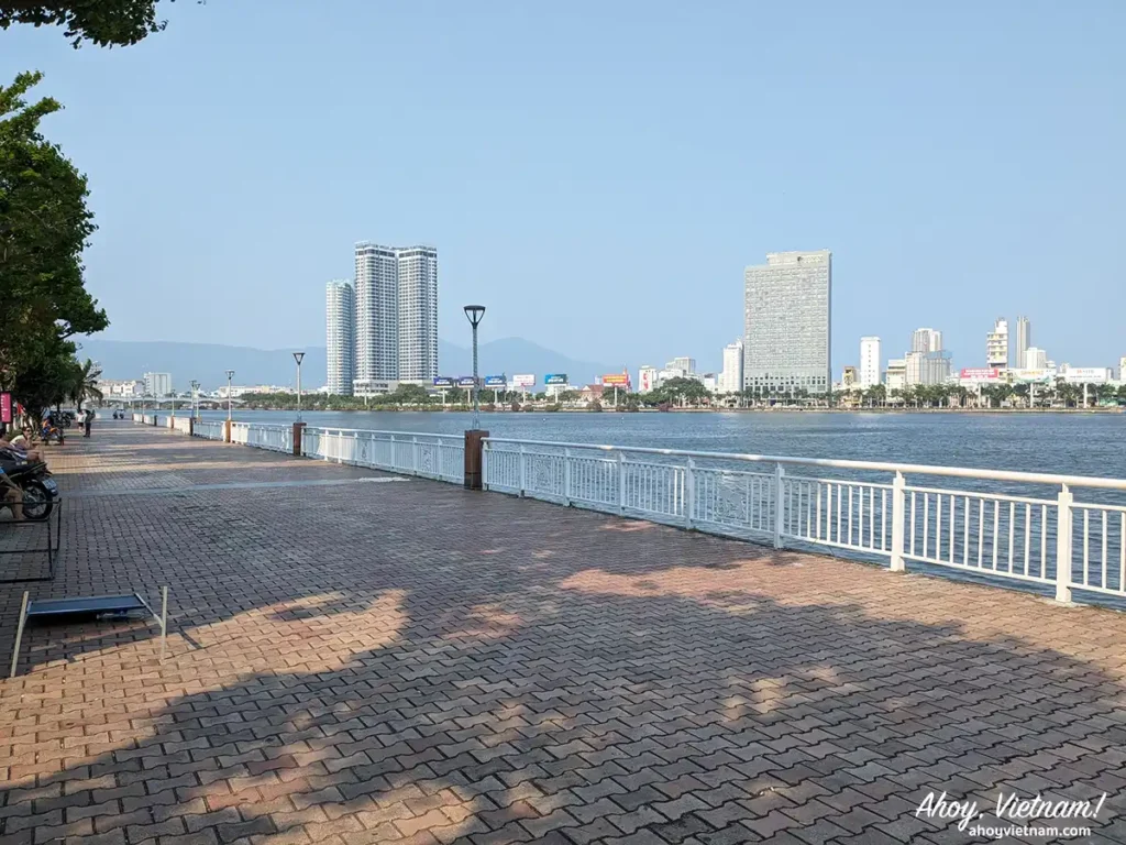 The walking path along the Han River in Hai Chau for those wondering where to stay in Da Nang, with buildings and the Son Tra Mountain in the background.