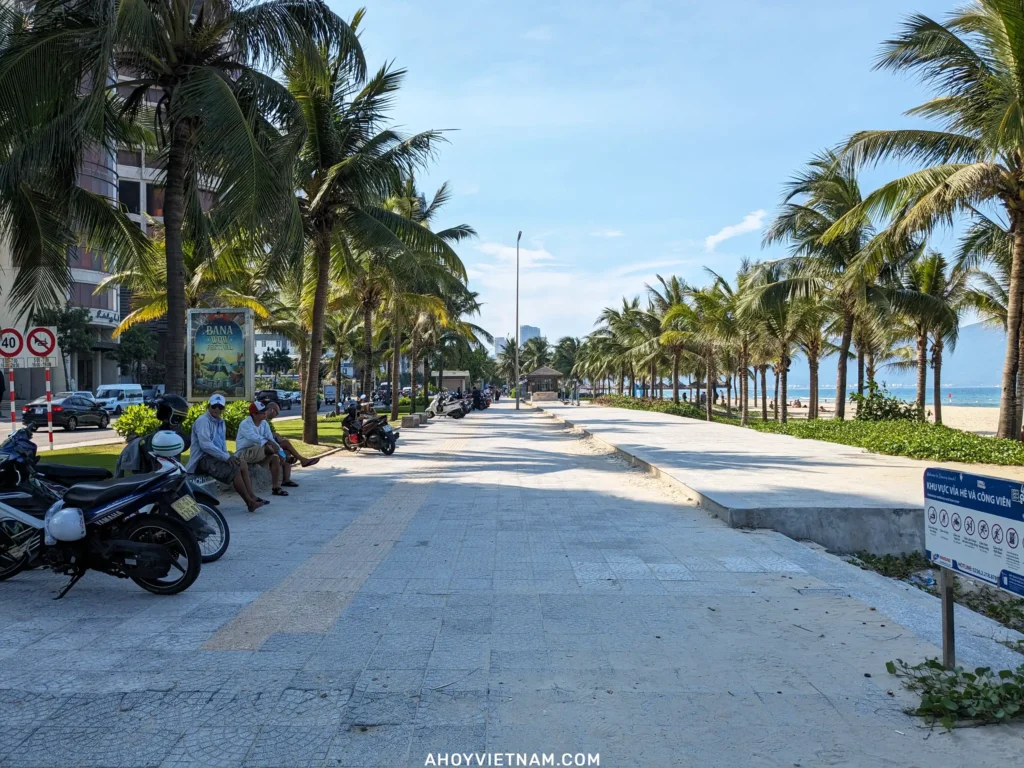 The walking path lined with palm trees and locals at My Khe Beach in Da Nang, Vietnam.