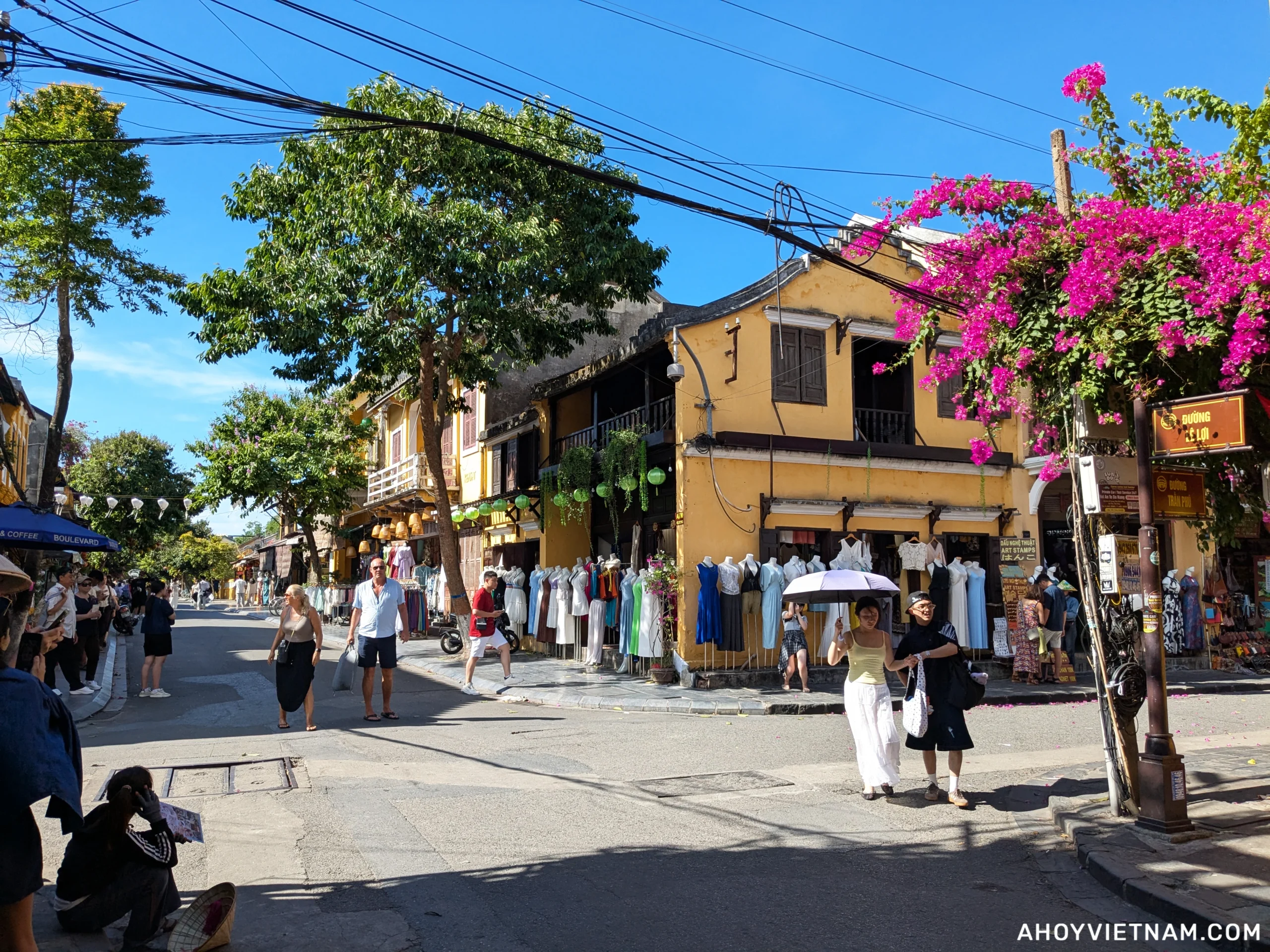 Tourists and pink flowers at the intersection of Tran Phu Street and Le Loi Street in Hoi An Old Town