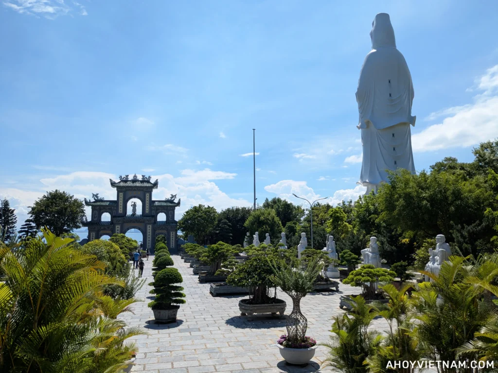 Bonsai trees, Buddhist sculptures, and the towering Lady Buddha statue in the background
