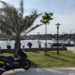 My black Honda PCX 150 scooter parked along the Thu Bon River in Hoi An.