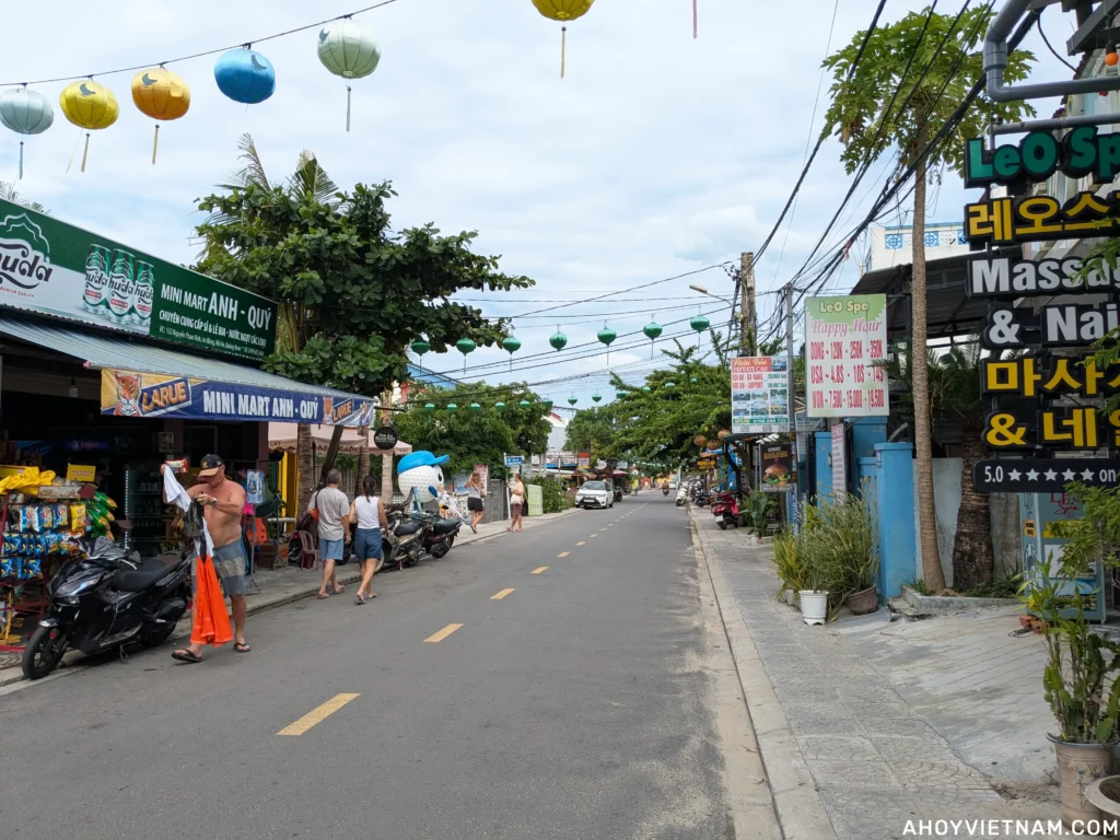 Tourists, shops, and scooters along Nguyen Phan Vinh Street at An Bang Beach in Hoi An.