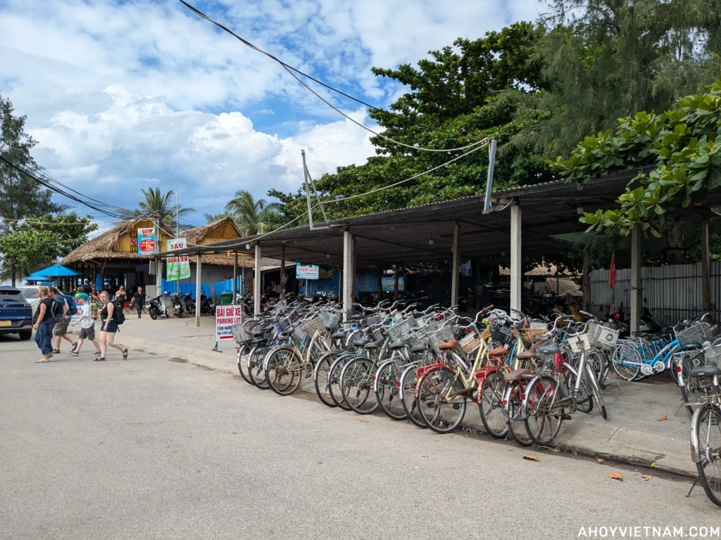 A parking lot with bicycles and scooters on Hai Ba Trung Street at An Bang Beach.