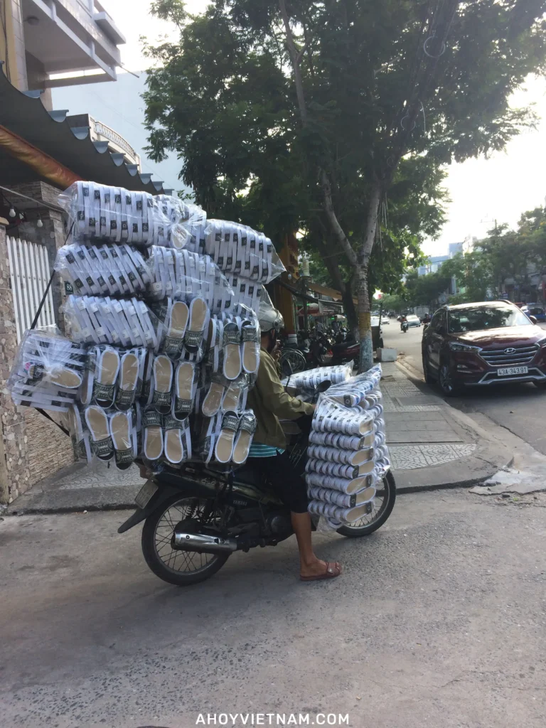 A man on a scooter in Da Nang, carrying hundreds of flip-flops in sealed bags.
