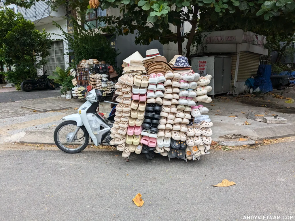 A parked scooter in Vietnam, carrying hundreds of sandals and hats on the back.