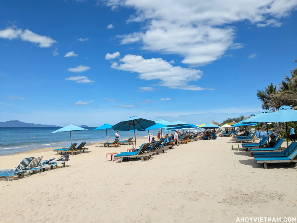 Sun loungers and tourists on the sand at An Bang Beach in Hoi An.