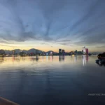 Sunset over the Han River in Da Nang, with mountains in the distance and buildings with neon lights.