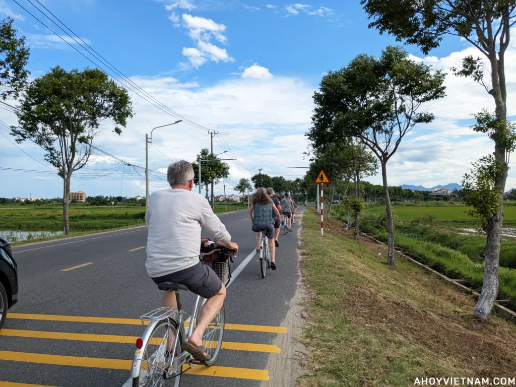Tourists bicycling on Hai Ba Trung Street through the rice fields in Hoi An.