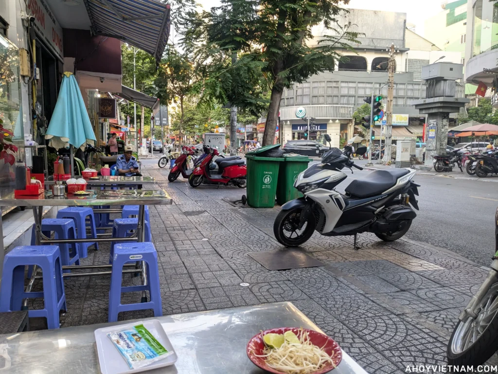 Scooters parked in front of shops in Ho Chi Minh City, including a white Yamaha NVX 155.