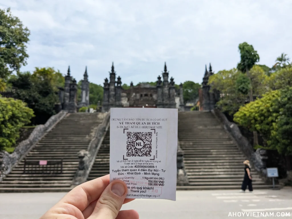 Holding up my combo ticket to Hue Imperial City and the tombs of Khai Dinh, Minh Mang, and Tu Duc outside the steps of Khai Dinh tomb.