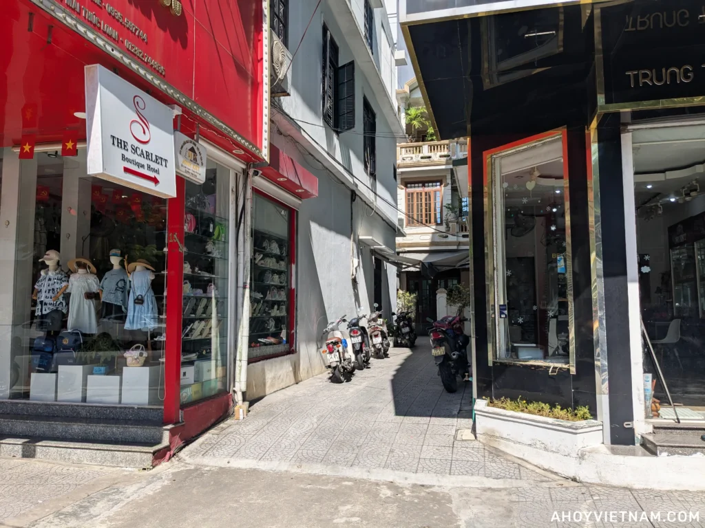 A sign reading "The Scarlett Boutique Hotel" hanging in front of a small alley leading to the hotel