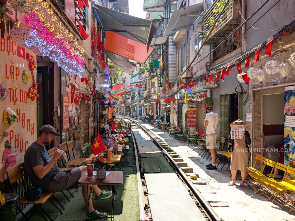 Looking down the train tracks at Hanoi Train Street, with guests seated at coffee shops