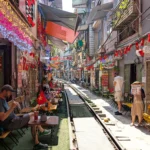 Looking down the train tracks at Hanoi Train Street, with guests seated at coffee shops