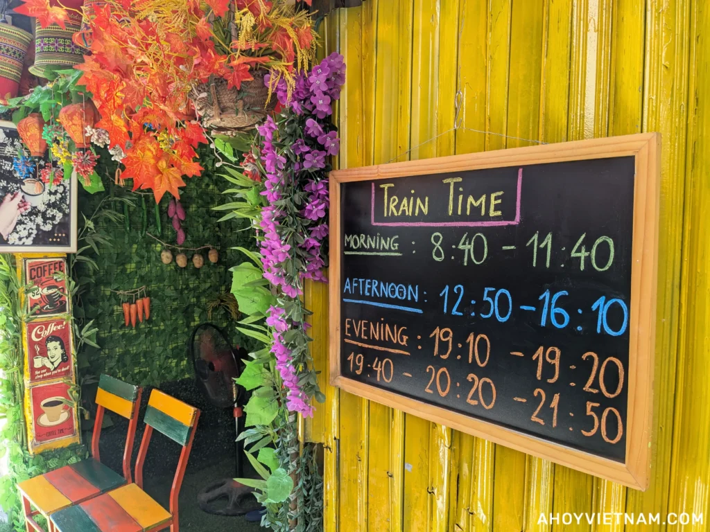 A sign showing the Hanoi Train Street schedule outside a coffee shop