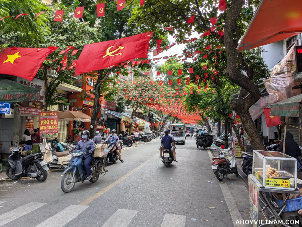 Vietnamese flags and scooters inside Hanoi's Old Quarter in Vietnam
