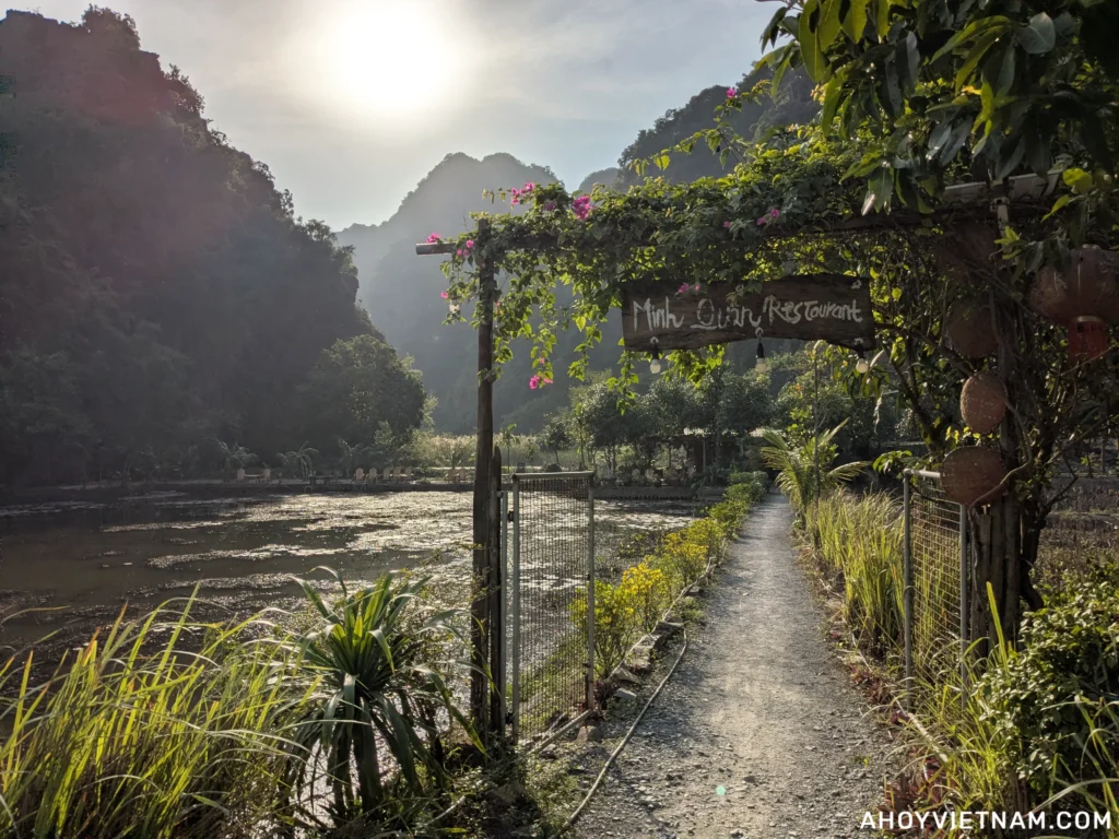 Heading into Minh Quan Restaurant in Ninh Binh, with trees, a lake, and limestone karsts in the distance