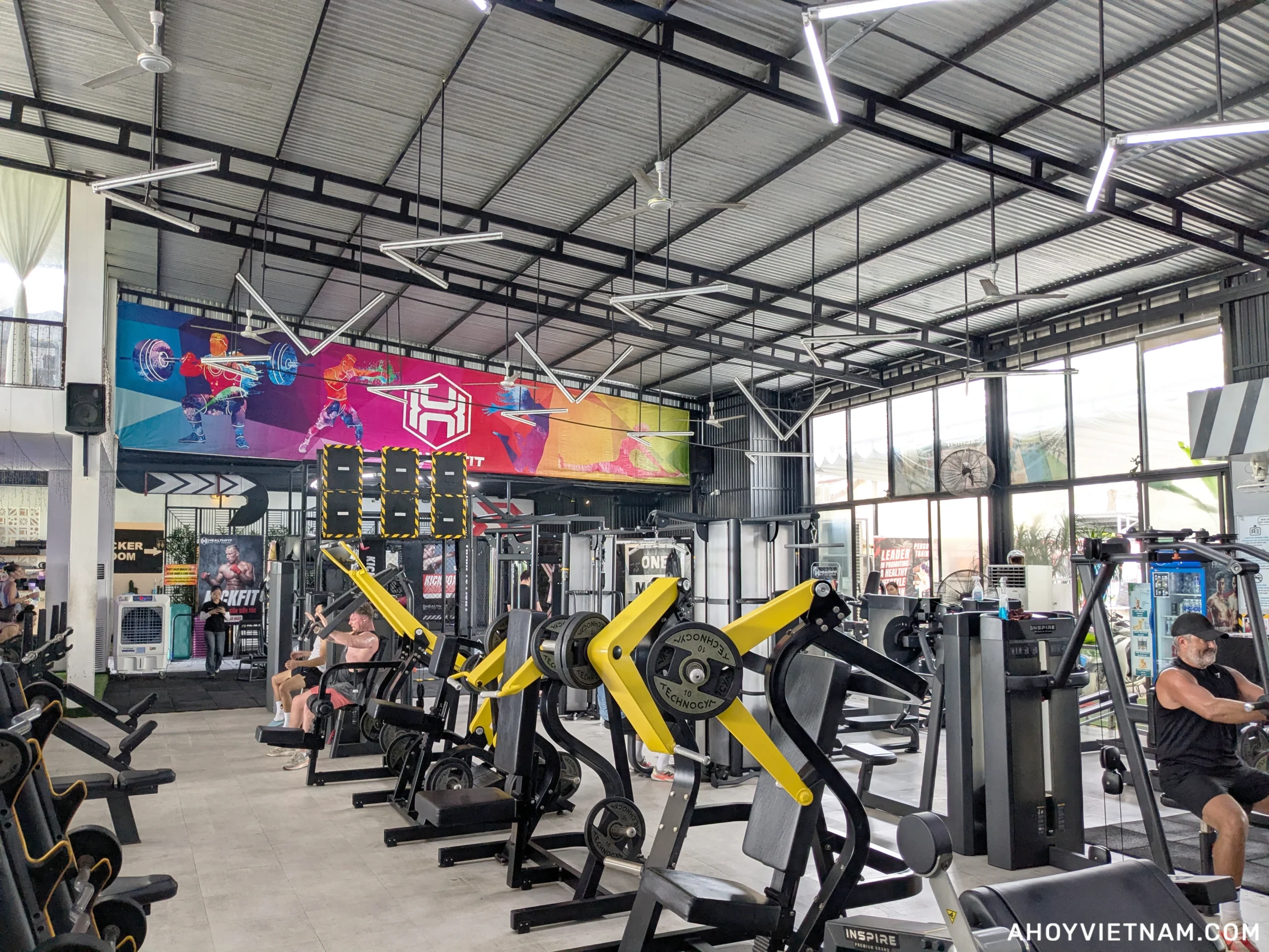 A lot of exercise machines and people training inside HealthFit Gym in Hoi An, Vietnam